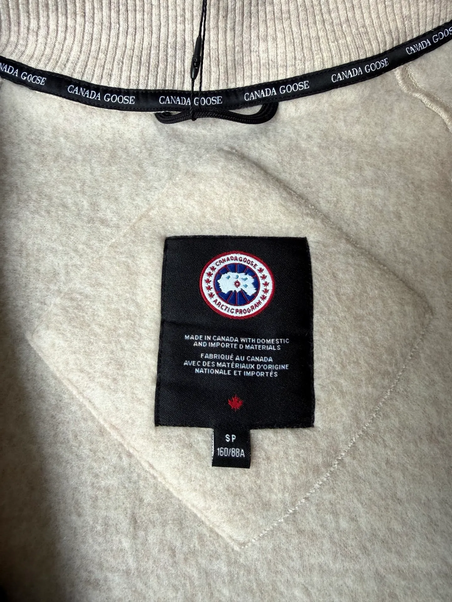 P620 Canada Goose Fleece Wool Baseball Jacket Fabric selection: Wool fleece fabric blended with wool as the main body and a very small amount of spandex and polyester fiber. Wool is a core natural ingredient that provides unparalleled temperature regulation, antibacterial and anti-odor properties and a skin-friendly feel. The feeding of a small amount of spandex gives the fabric a certain degree of four-way elasticity, making it non-restrictive during daily activities. As the basis of fleece's structure, polyester fiber enhances the fabric's durability, wrinkle resistance and quick-drying properties. It contributes to the loft of the fleece and provides functions such as trapping air.  Detail 1: The sleeves and hem are closed with 2×2 ribbing. Its strong elasticity can closely fit wrists and waists of different thicknesses, forming an effective 'seal' to prevent cold wind from blowing back. It can still maintain its original shape after repeated stretching and use, and is not easy to loose and deform. And the ribbed cuffs can convey a sense of design and enhance the visual beauty.  Detail 2: The combination of hood design and elastic buckle improves warmth and windproof performance when wearing. Accessories: Customized elastic drawstring, elastic buckle, custom zipper pendant, custom armband Size: S M L Color: Black Gray Mickey